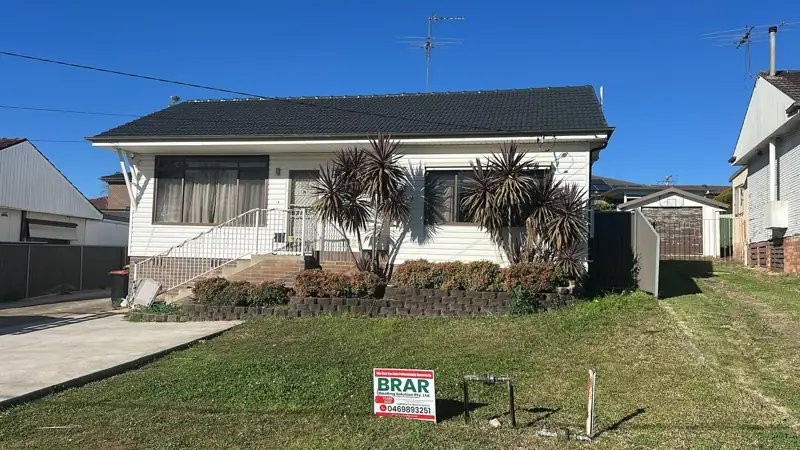 Finished charcoal tile roof on a white home with a Brar Roofing sign on the lawn