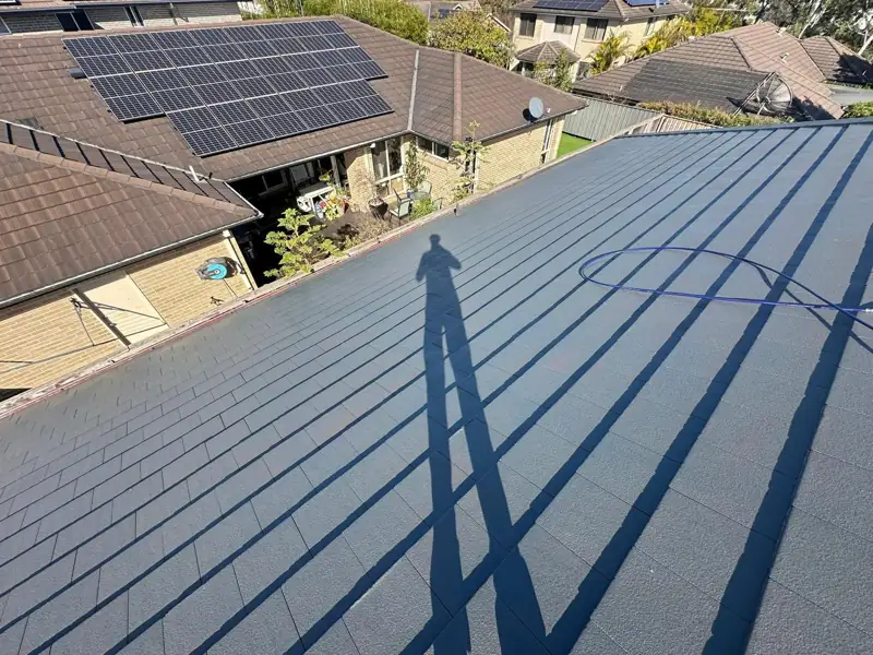 Flat-profile tile roof after restoration, with solar panels on the next roof