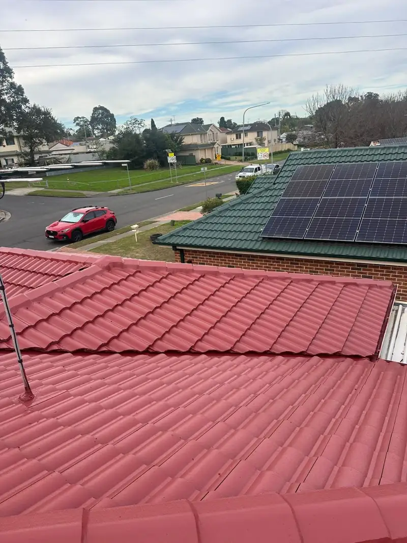 Finished red tile roof beside a neighbouring home with solar panels