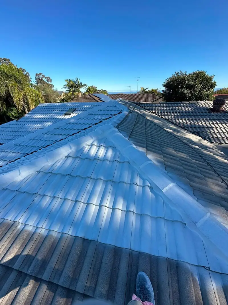 Blue roof coating being sprayed onto a tile roof
